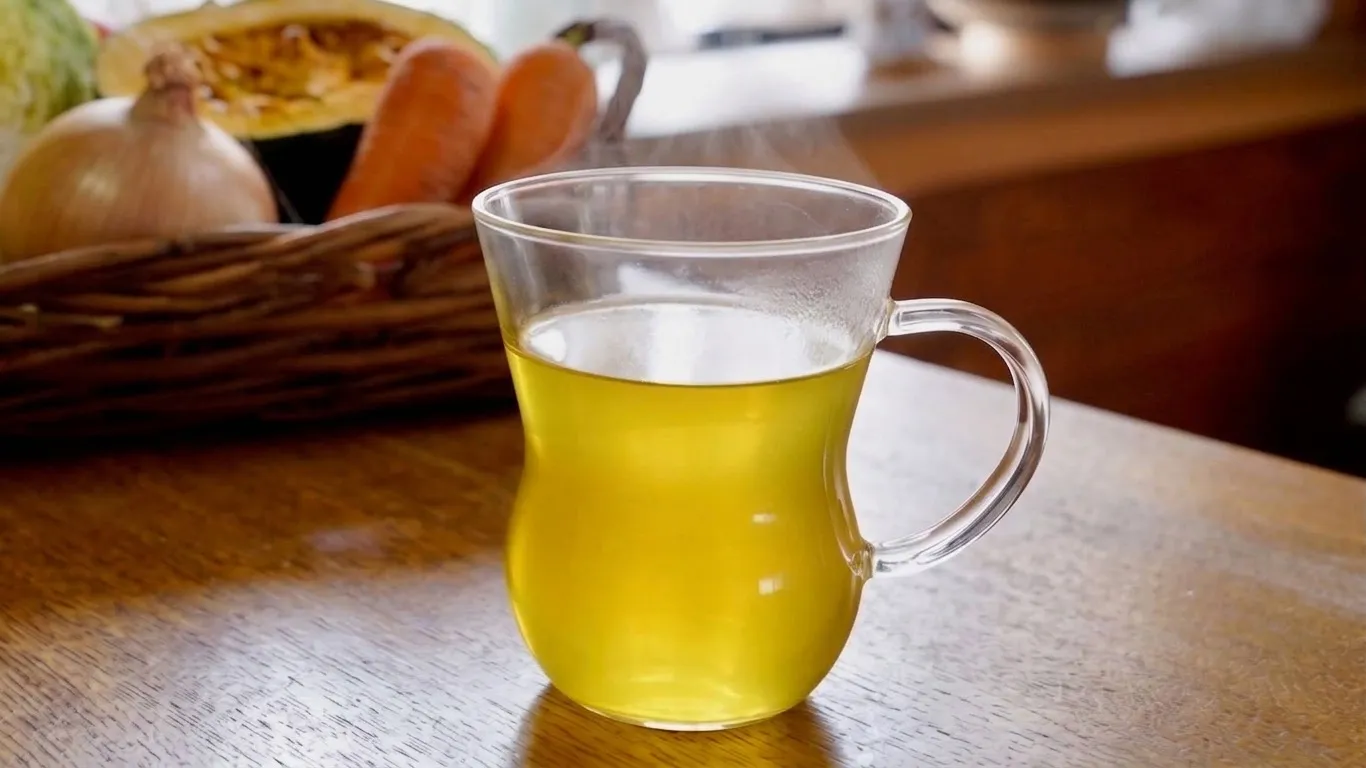 透明なカップに注がれた黄金色の野菜スープ